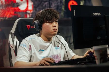 LPL top laner competing on stage during a League of Legends match, focused at his gaming setup under esports stage lighting